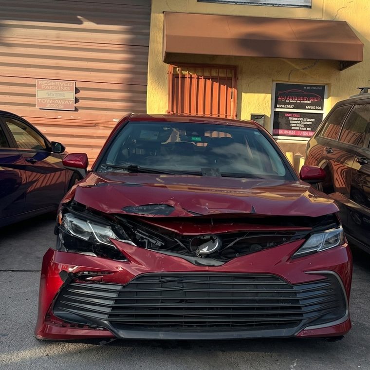 Toyota Camry rojo con el frente destrozado antes de la reparación